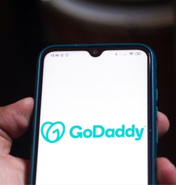 Hand holding a phone with GoDaddy logo on the screen