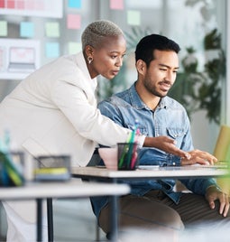 Woman showing a man how to do something on a laptop