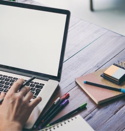 Laptop open with notebooks lying either side