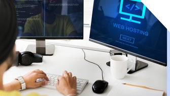 Person taps on keyboard in front of two desktop screens looking at web hosting