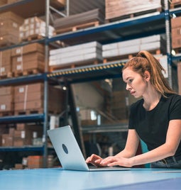 Woman working at a laptop in a warehouse