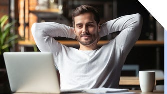 Man with arms behind his head relaxing as he looks at a laptop