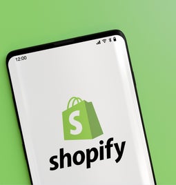 Green background with a phone showing the shopify logo