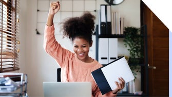 Lady punches air with joy in front of her laptop