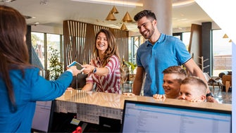 Hotel receptionist hands smiling family a room key