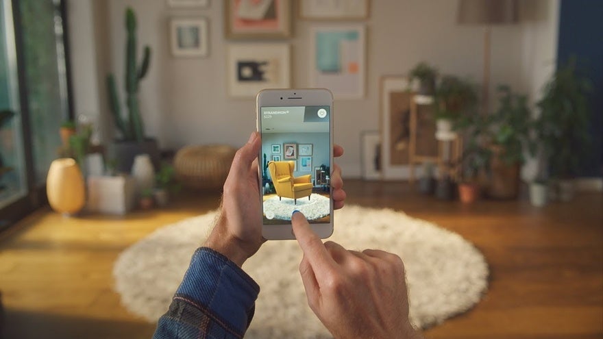 IKEA digital AR enhanced shopping A person uses IKEA's AR tool to visualize a yellow chair in their room