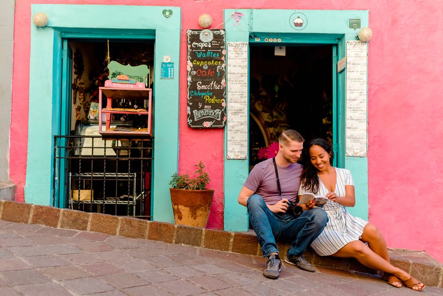 Spanish and Go Jim and May sitting on the street in front of a pink shop