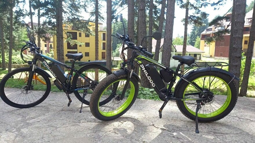 Testimony photo 1 Two bikes on a path in front of trees with some buildings in the background.