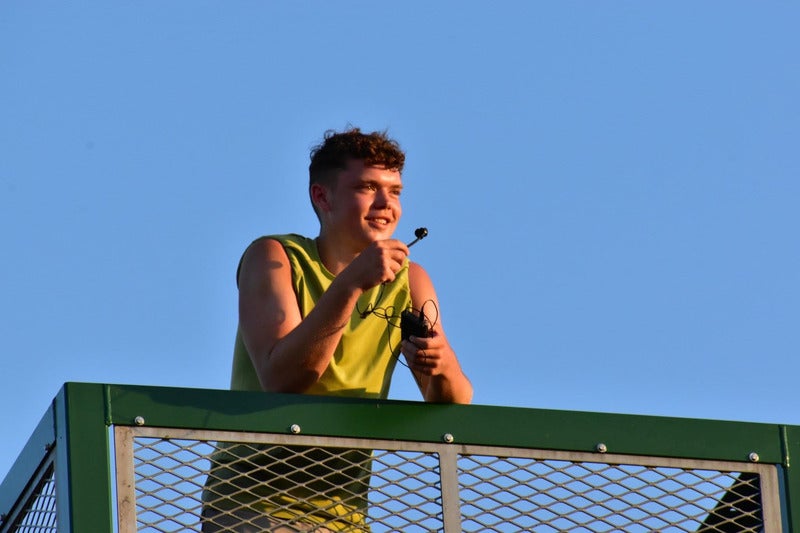 unnamed (1) (1) boy in yellow vest talking into microphone at sunset