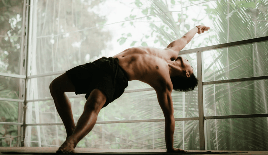 Bayu1 A man stretching into a yoga pose surrounded by nature.