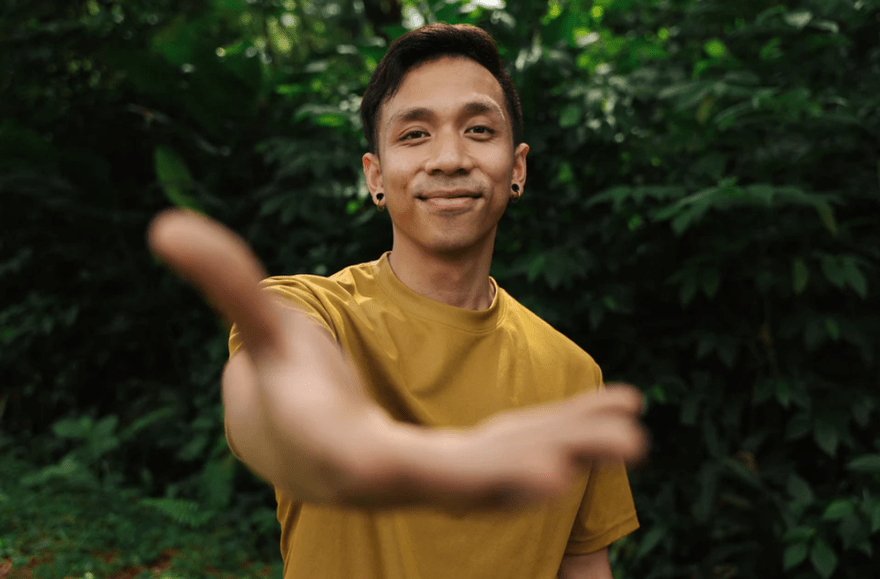 Bayu3 Bayu extending his hand out to the camera smiling in a yellow top.