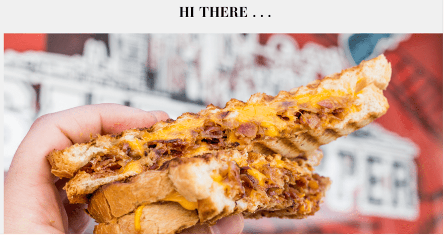Grilled cheese A person holding a grilled cheese sandwich with bacon and cheese. The sandwich is golden brown and looks melted and gooey. The person is smiling and holding up the sandwich for a photo.