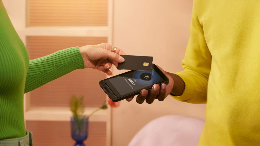 POS_Go_Launch_Blog_Header_Image image of green jumper-wearing person tapping a card agaisnt a phone held my a person in a yellow jumper