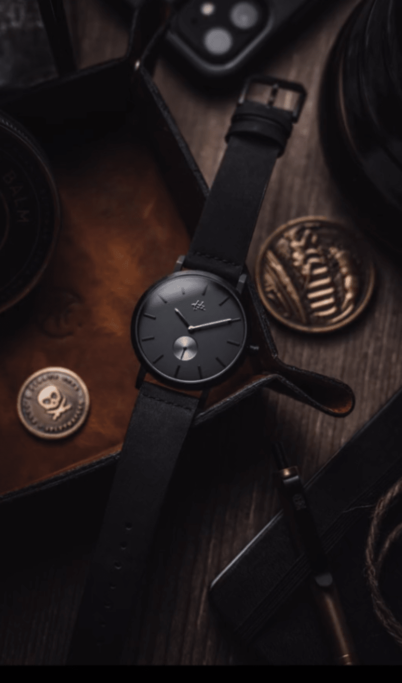 Screenshot 2023-09-13 095218 dark, moody pic of a black matte watch on a wooden desk