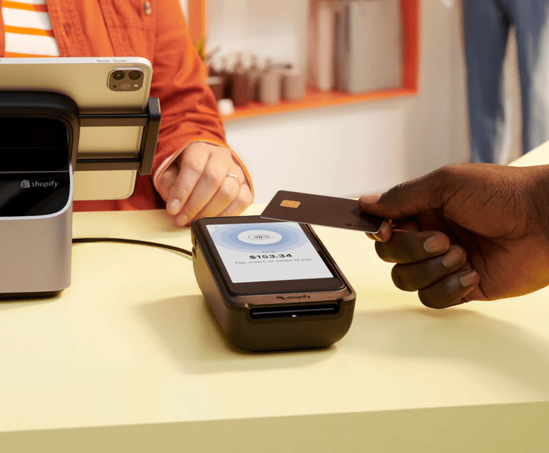 shopify POS terminal a hand placing a card against a terminal