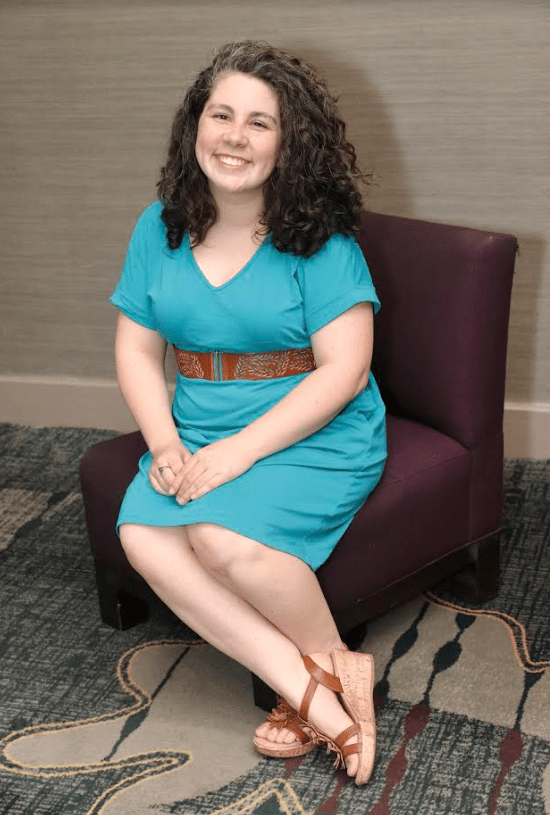 Vicky Weber An image of Vicky Weber, wearing a blue belted dress, sitting on a purple chair.